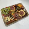Grand (Serves 8–10): Includes 4–5 artisanal cheeses, 3 cured meats, fresh fruit, nuts, 1 dip or spread, honey and jam, olives, crackers, and a sweet treat. Tray or container is subject to availability and may vary in shape and material. Wooden boards available for rent